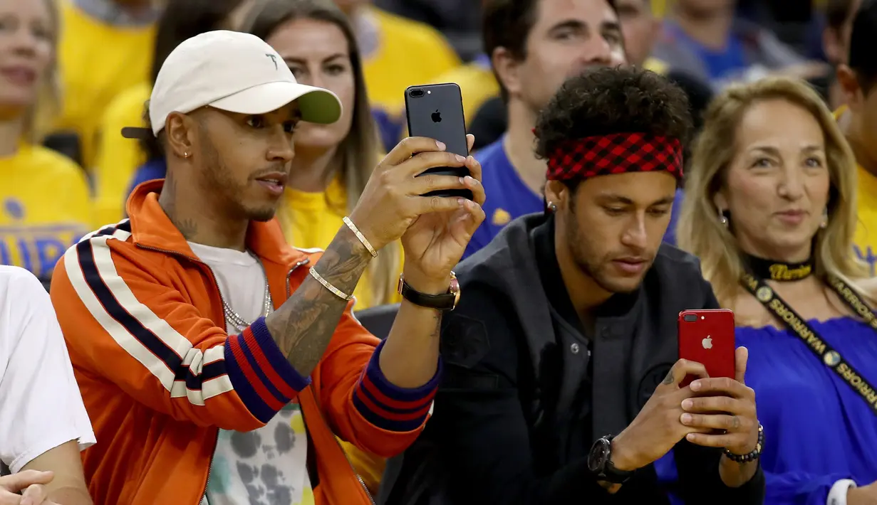 Pembalap Formula 1, Lewis Hamilton dan pemain Barcelona, Neymar Jr merekam pertandingan gim kedua Final NBA antara Cleveland Cavaliers melawan Golden State Warriors di Oracle Arena, Oakland, California, AS, (4/6). (Ezra Shaw/Getty Images/AFP)