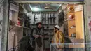Seorang pedagang senjata Hakimullah Afridi (kiri) memperlihatkan senapan otomatis buatan lokal kepada pelanggan di tokonya, Darra Adamkhel, Pakistan, 14 Desember 2022. Selama beberapa dekade, militansi dan perdagangan narkoba di pegunungan sekitar Darra Adamkhel membuatnya mendapatkan reputasi sebagai titik jalan "wild west" antara Pakistan dan Afghanistan. (Abdul MAJEED/AFP)