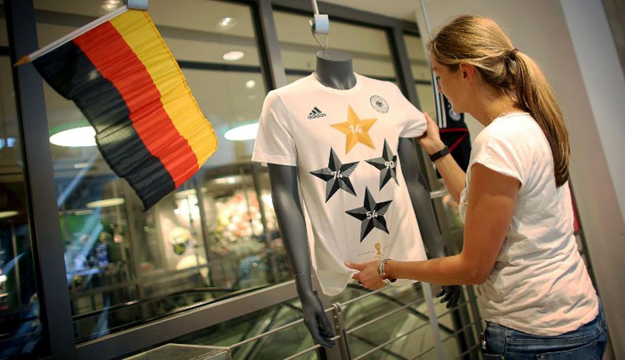 Petugas toko di Frankfurt, (14/7/2014), merapikan kaos berlogo federasi sepak bola Jerman dengan empat bintang. Tanda bintang pada kaos timnas melambangkan jumlah capaian gelar juara di ajang Piala Dunia. (AFP PHOTO/DPA/Fredrik VON Erichsen)
