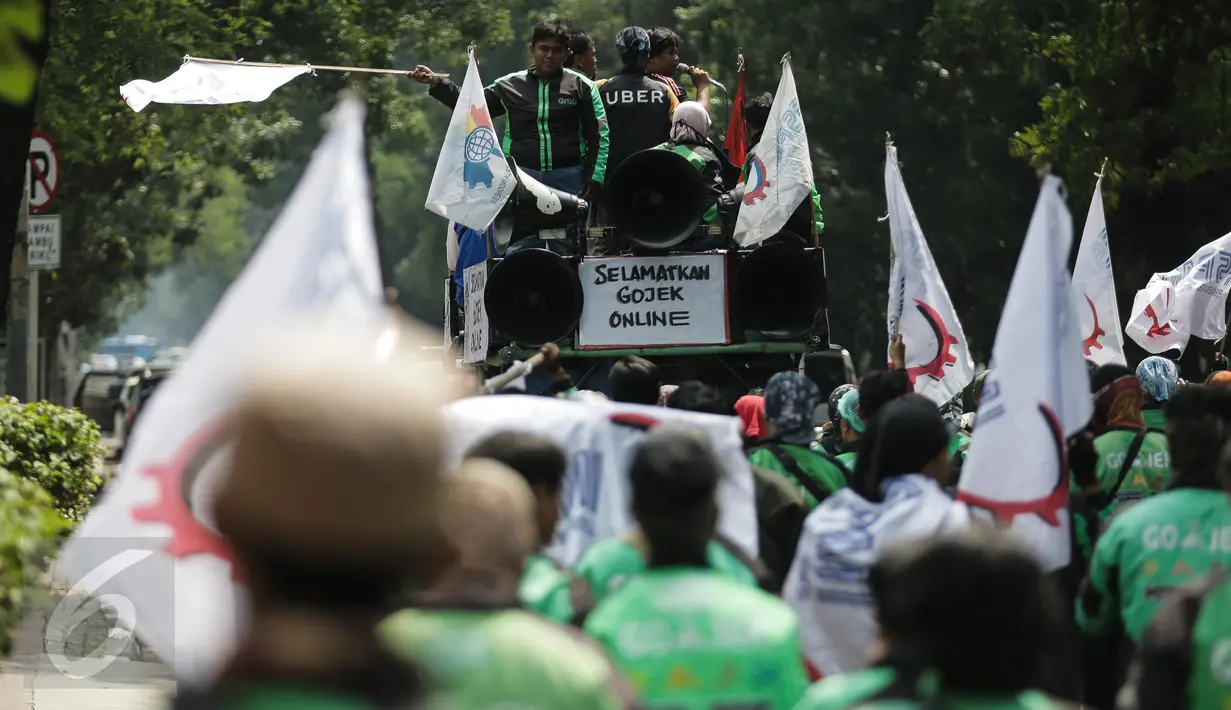 Massa pengemudi ojek online menaiki mobil komando sambil berorasi saat unjuk rasa menuju Istana Negara, Jakarta, Senin (15/5). Aksi tersebut menuntut adanya perbaikan pemberlakuan tarif dasar yang dirasa merugikan pengemudi. (Liputan6.com/Faizal Fanani)