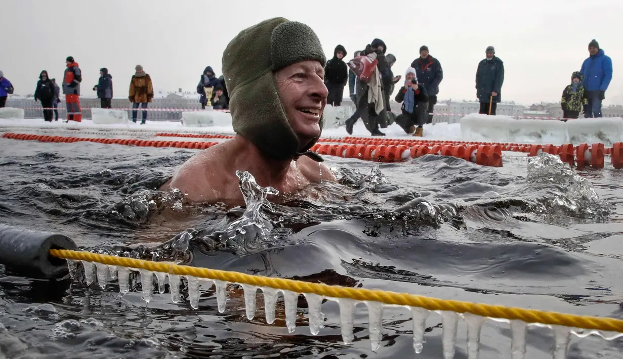 Seorang peserta tersenyum saat mengikuti kompetisi renang di perairan es di sungai Neva selama Big Neva Cup of Ice Swimming di St.Petersburg, Rusia, (4/3). (AP Photo/Dmitri Lovetsky)