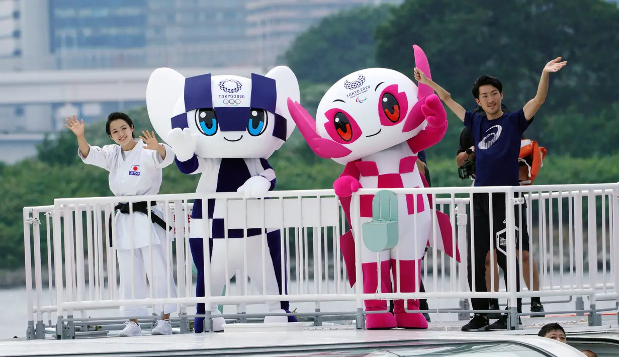 Maskot Olimpiade dan Paralimpik Tokyo 2020, Miraitowa (kiri) dan Someity (kanan) melambaikan tangan saat menaiki perahu di Rainbow Bridge, Tokyo, Jepang, Minggu (22/7). Miraitowa dan Someity resmi diperkenalkan kepada publik. (AP Photo/Eugene Hoshiko)