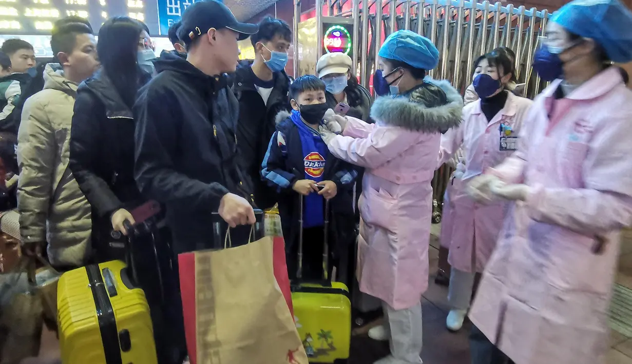Petugas memeriksa suhu tubuh seorang penumpang di Stasiun Kereta Api Yingtan di Nanchang di Provinsi Jiangxi Tengah, China (22/1/2020). Sebanyak 17 orang meninggal akibat terinfeksi virus corona. (AFP Photo/STR)