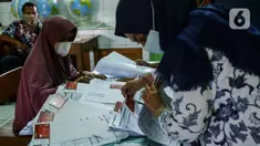 Petugas mencari data warga penerima manfaat saat pencairan bantuan sosial tunai (BST) di SDN Kembangan Utara 05 Pagi, Jakarta, Rabu (31/3/2021). Program BST sebesar Rp300 ribu dari Kemensos ini disalurkan melalui RT-RT se kelurahan Kembangan Utara melalui ATM Bank DKI. (Liputan6.com/Johan Tallo)