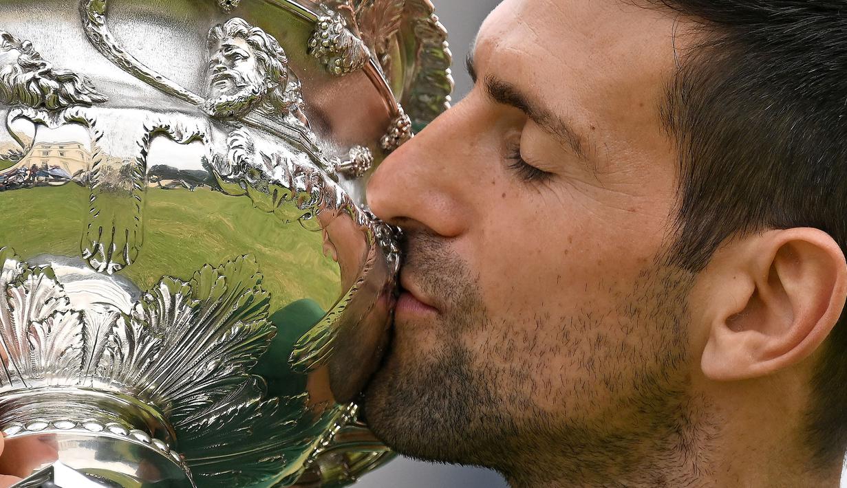 <p>Petenis tunggal putra Serbia, Novak Djokovic berpose mencium trofi Norman Brooks Challenge Cup setelah menjadi juara pada Australia Open 2023 di Government House, Melbourne, Australia, Senin (30/01/2023). Djokovic berhasil mengalahkan petenis Yunani, Stefanos Tsitsipas di babak final dengan skor 6-3, 7-6(7-4), 7-6(7-5). (AFP/Saeed Khan)</p>