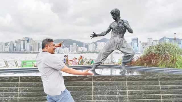 Seorang turis berfoto di depan patung Bruce Lee, di kawasan Avenue of Stars yang menjadi tempat wisata di Hong Kong. (Liputan6/Benedikta Miranti)
