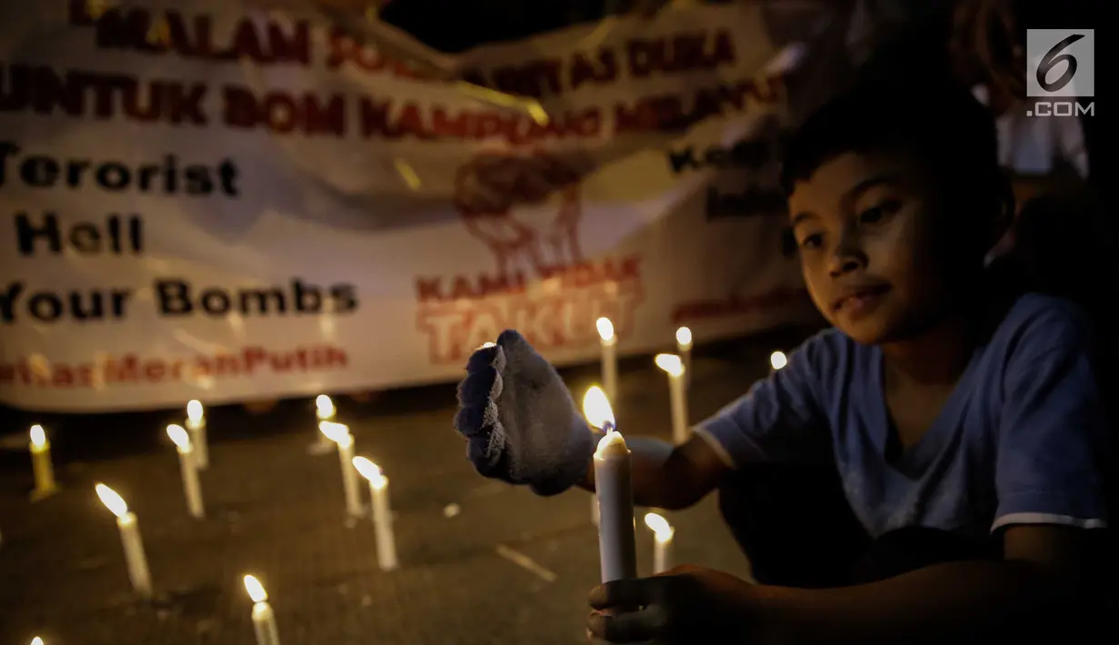 assa dari Solidaritas Merah Putih menggelar aksi lilin dan tabur bunga di lokasi bom Terminal Kampung Melayu, Jakarta, Kamis (25/5). Aksi tersebut sebagai bentuk malam solidaritas duka untuk bom Kampung Melayu.(Liputan6.com/Faizal Fanani)