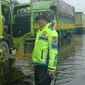 Personel Polres Pelalawan mengamankan jalur di Jalan Lintas Timur kilometer 83 karena terendam banjir. (Liputan6.com/M Syukur)