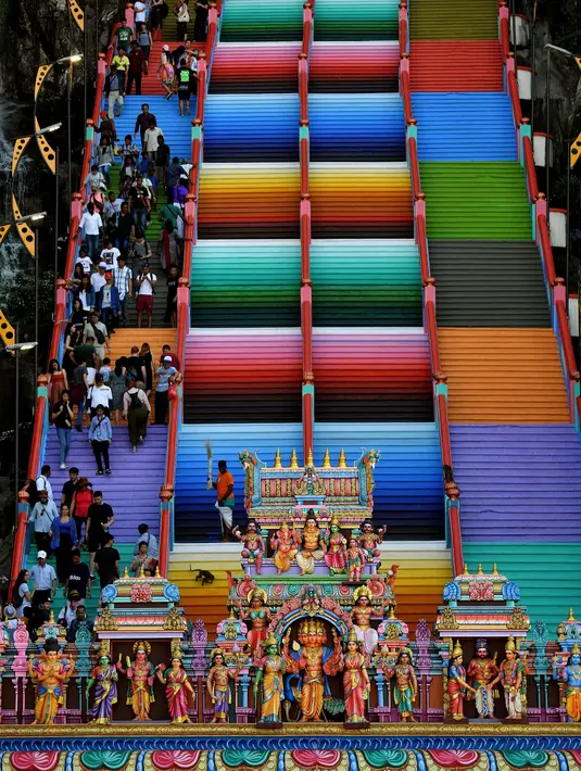 Pengunjung menaiki tangga 272 langkah yang baru dicat, jalan untuk menuju kuil Batu Caves di Kuala Lumpur, 30 Agustus 2018. Pengelola disebut tak mendapat izin dari Kementerian Kebudayaan Malaysia sebelum melakukan renovasi tersebut (AFP/Manan VATSYAYANA)