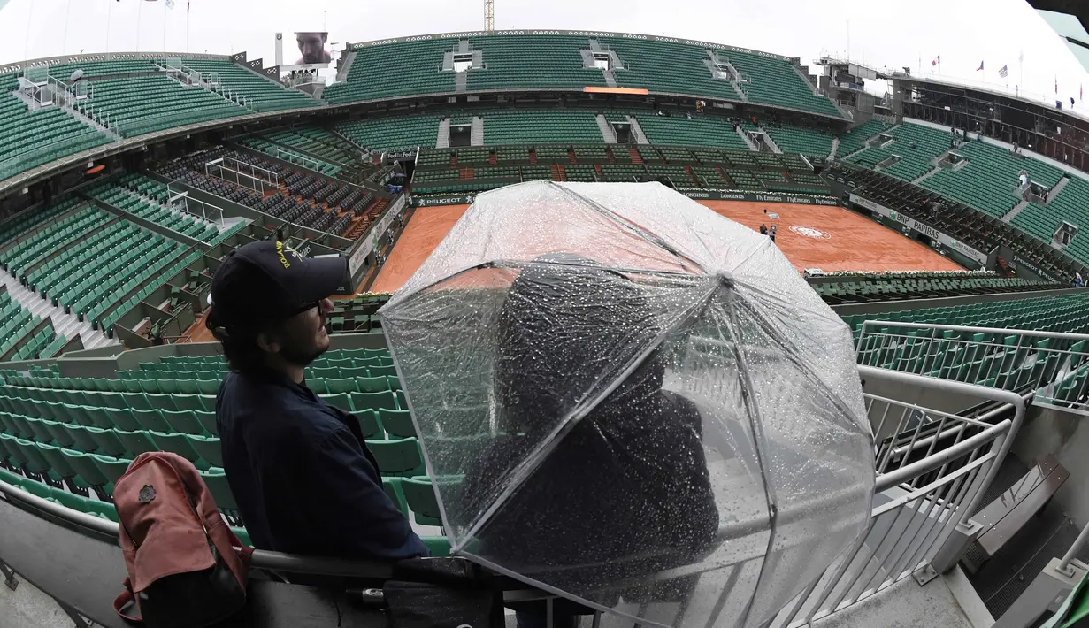 Penonton menanti hujan reda untuk menyaksikan turnamen   Prancis Terbuka 2016 di Roland Garros (28/5/2016).(AFP/Miguel Medina)