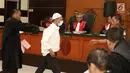 Terdakwa kasus penembakan dr Letty Sultri, dr Helmi menghampiri kuasa hukumnya saat sidang mendengarkan dakwaan di PN Jakarta Timur, Kamis (29/3). Helmi didakwa telah menembak istrinya hingga tewas pada 9 November 2017. (Liputan6.com/Herman Zakharia)