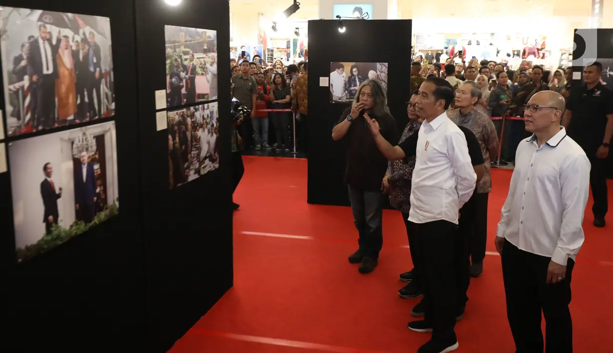 Presiden Joko Widodo atau Jokowi memerhatikan foto-foto yang ditampilkan dalam pameran foto 'Membangun Indonesia'  di Jakarta, Selasa (12/11/2019). Pameran foto itu menampilkan sejumlah capaian kinerja pemerintahan Presiden Joko-Widodo dan Wakil Presiden Jusuf Kalla. (Liputan6.com/Angga Yuniar)