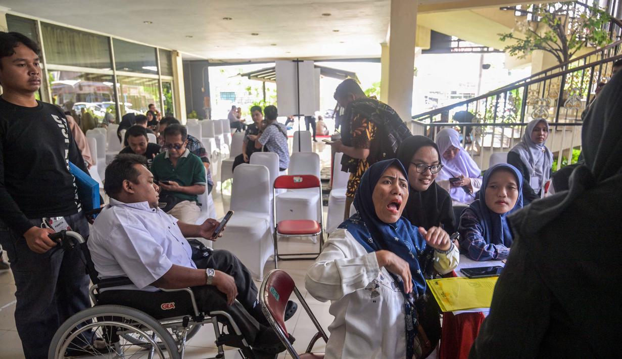 Penyelenggara berharap bursa kerja ini mampu menjangkau sekitar 7.000 penyandang disabilitas. Tampak dalam foto, para penyandang disabilitas menunggu untuk menyerahkan formulir lamaran mereka dalam bursa kerja yang diselenggarakan pemerintah daerah di Surabaya, Jawa Timur, pada Selasa 25 November 2025. (JUNI KRISWANTO/AFP)