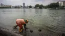Seorang petugas PSSU atau pasukan oranye membersihkan pinggiran Danau Sunter, Jakarta, Rabu (27/12). Kegiatan bersih-bersih ini dilakukan terkait rencana Pemkot Jakarta Utara menggelar perayaan tahun baru di Danau tersebut. (Liputan6.com/Faizal Fanani)