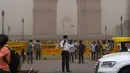 Seorang polisi lalu lintas menutupi wajahnya saat badai debu menyelimuti New Delhi, India, Rabu (2/5). Selain menewaskan 77 orang, sebanyak 143 lainnya juga terluka. (CHANDAN KHANNA/AFP)