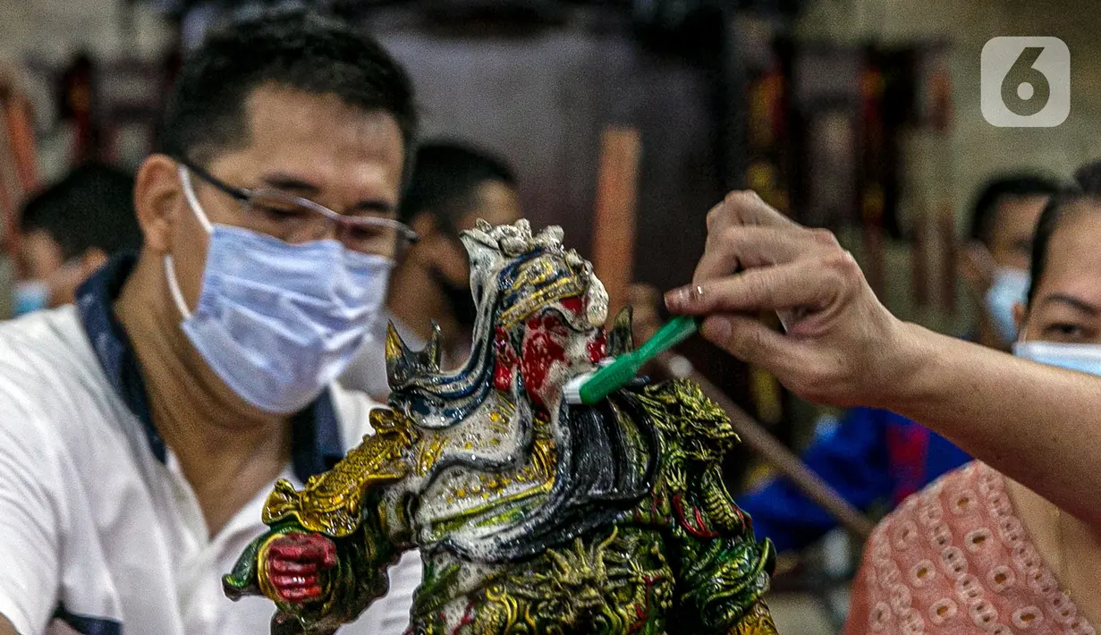 Para jemaat menyikat patung yang ada di Vihara Amurva Bhumi, Jakarta, Kamis (4/2/2021). Ritual mencuci patung dewa serta bersih-bersih ini dilakukan dalam rangka menyambut perayaan Tahun Baru Imlek 2572. (Liputan6.com/Faizal Fanani)