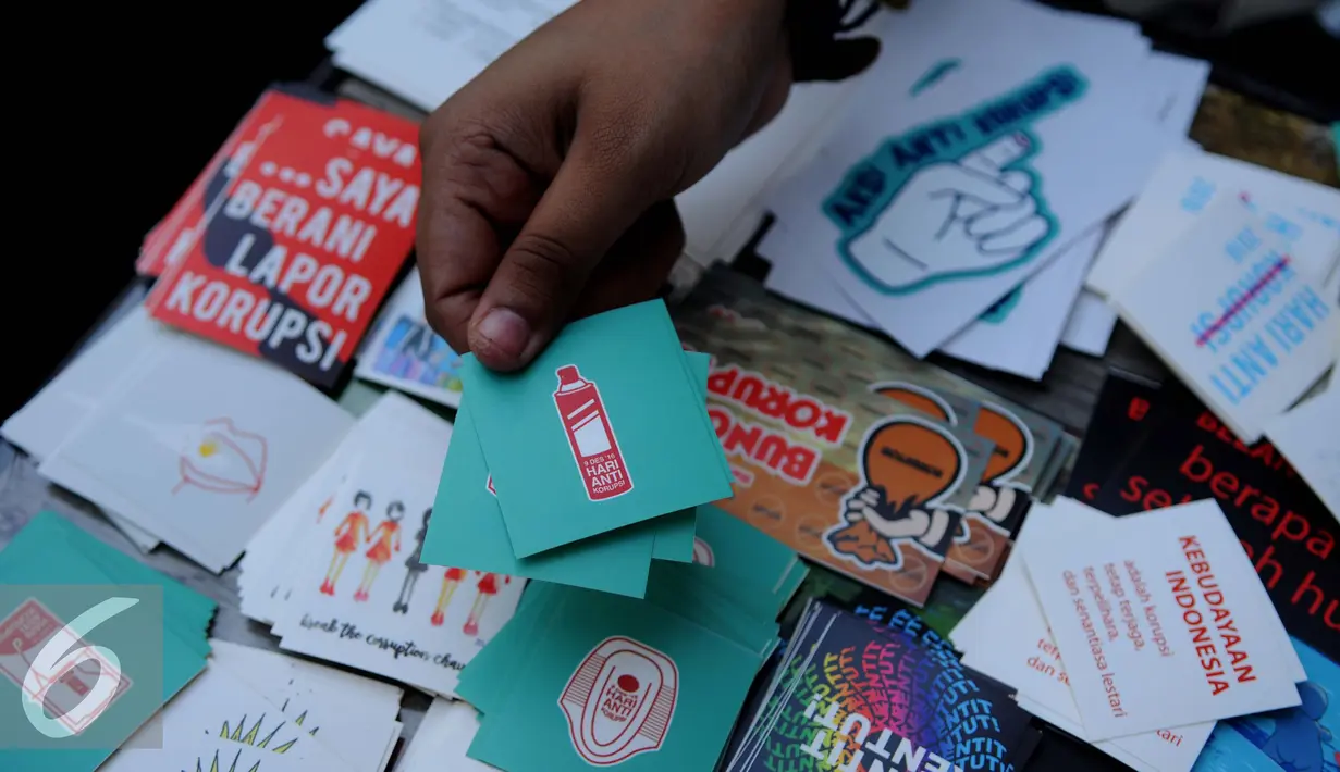 Pengunjung menunjukkan stiker saat Pameran Peringatan Hari Anti Korupsi oleh ICW, Jakarta, Jum’at (9/12). ICW memperingati Hari Anti Korupsi Dunia dengan Pameran instalasi anti korupsi, diskusi dan konser musik. (Liputan6.com/Gempur M Surya)