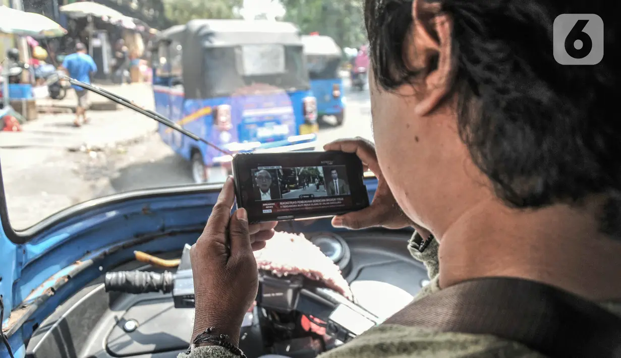 Sopir bajaj menyaksikan tayangan pada gawainya yang menyiarkan langsung rekonstruksi pembunuhan Brigadir Nofriansyah Yosua Hutabarat alias Brigadir J melalui smartphone di Pasar Senen, Jakarta Pusat, Selasa (30/8/2022). Rekonstruksi ulang pembunuhan Brigadir J yang dihadiri oleh lima tersangka, yakni Ferdy Sambo, Bharada Richard Eliezer (Bharada E), Bripka Ricky Rizal, Kuat Ma'ruf, dan Putri Candrawathi itu menjadi perhatian warga dari berbagai kalangan untuk menyaksikan secara langsung meski hanya melalui siaran televisi atau gawai. (merdeka.com/Iqbal S. Nugroho)