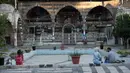Warga Suriah bermukim di kompleks Takiyya di kota tua Damaskus, Suriah, (18/7). Kompleks Takiyya adalah bangunan kuno dengan halaman lanskap yang dibangun di tepi Sungai Barada. (AP Photo / Hassan Ammar)