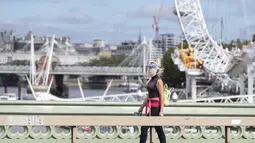 Seorang wanita yang mengenakan pelindung wajah berjalan melewati London Eye di London, Inggris (8/9/2020). Angka resmi terbaru Inggris pada Selasa (8/9) menunjukkan bahwa korban meninggal akibat COVID-19 di negara tersebut telah mencapai 57.400. (Xinhua/Han Yan)