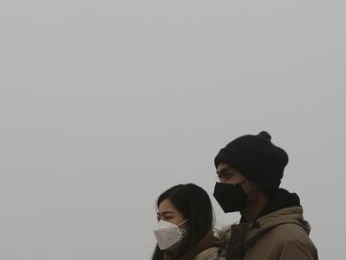 Pasangan mengenakan masker berjalan di Gunung Namsan di Seoul, Korea Selatan (10/12/2019). Korea Selatan telah mengeluarkan langkah-langkah darurat untuk polusi udara, setelah rekor tingkat debu halus menyelimuti sebagian besar negara dalam beberapa pekan terakhir. (AP Photo/Ahn Young-joon)