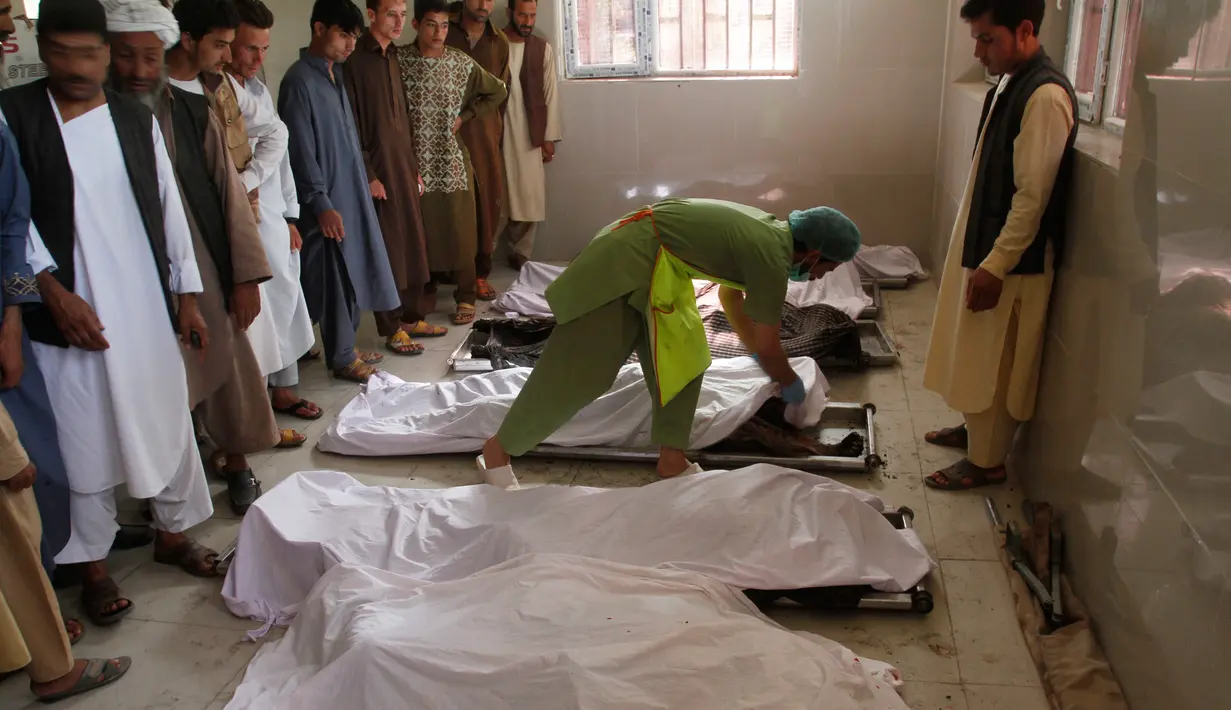 Seorang pria berdiri dekat mayat kerabtanya yang tewas, di sebuah rumah sakit di kota Herat, Afghanistan, Selasa (6/6). Sebuah bom sepeda motor meledak di luar sebuah masjid bersejarah dan menyebabkan tujuh orang tewas. (AP Photos/Hamed Sarfarazi)