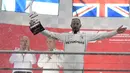 Pembalap Mercedes, Lewis Hamilton memegang trofi juara F1 GP Jerman di atas podium  Sirkuit Hockenheim, Minggu (22/7). Kemenangan ini diraih secara dramatis karena Hamilton mengawali balapan dari urutan ke-14. (AP/Jens Meyer)