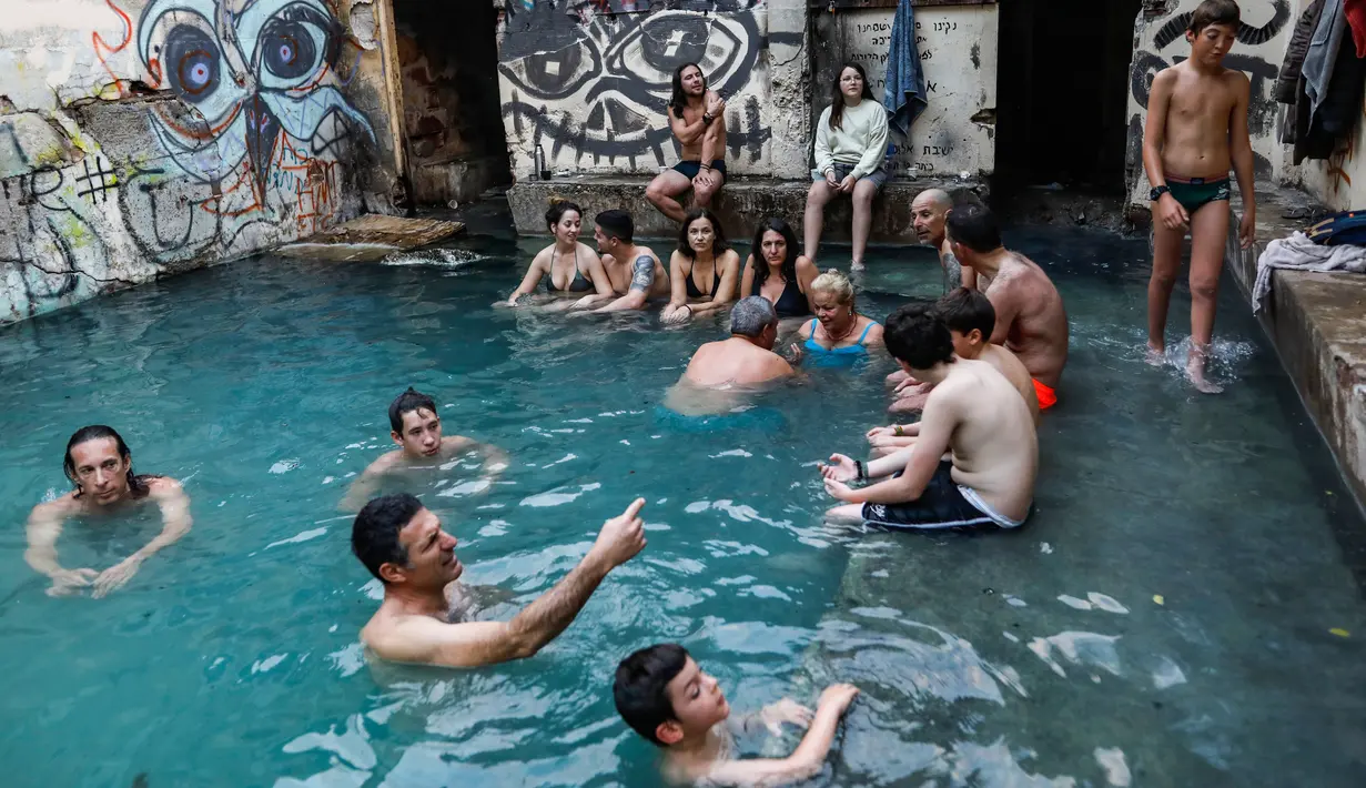 Wisatawan berendam di kolam air panas di ujung selatan Dataran Tinggi Golan yang dianeksasi Israel, dekat perbatasan dengan Yordania, 1 Maret 2019. Kolam dengan air panas itu berasal dari aliran pipa pengeboran di Lembah Hula. (MENAHEM KAHANA/AFP)