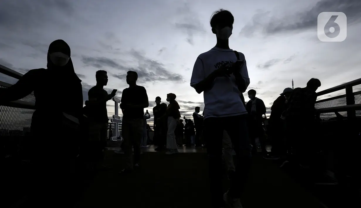 Warga mengisi libur Tahun Baru dengan menikmati pemandangan Kota Jakarta dari Skywalk Senayan Park, Sabtu (1/1/2022). Warga ramai-ramai datang untuk berburu foto pada spot-spot yang instagramable di Skywalk Senayan Park. (Liputan6.com/Johan Tallo)