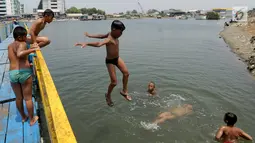 Sejumlah anak bermain dengan melompat ke air dekat tanggul laut Muara Baru di Penjaringan, Jakarta Utara, Minggu (1/9/2019). Anak-anak memanfaatkan sisi tanggul laut raksasa (giant sea wall) sebagai   tempat  bermain alternatif. (merdeka.com/Arie Basuki)