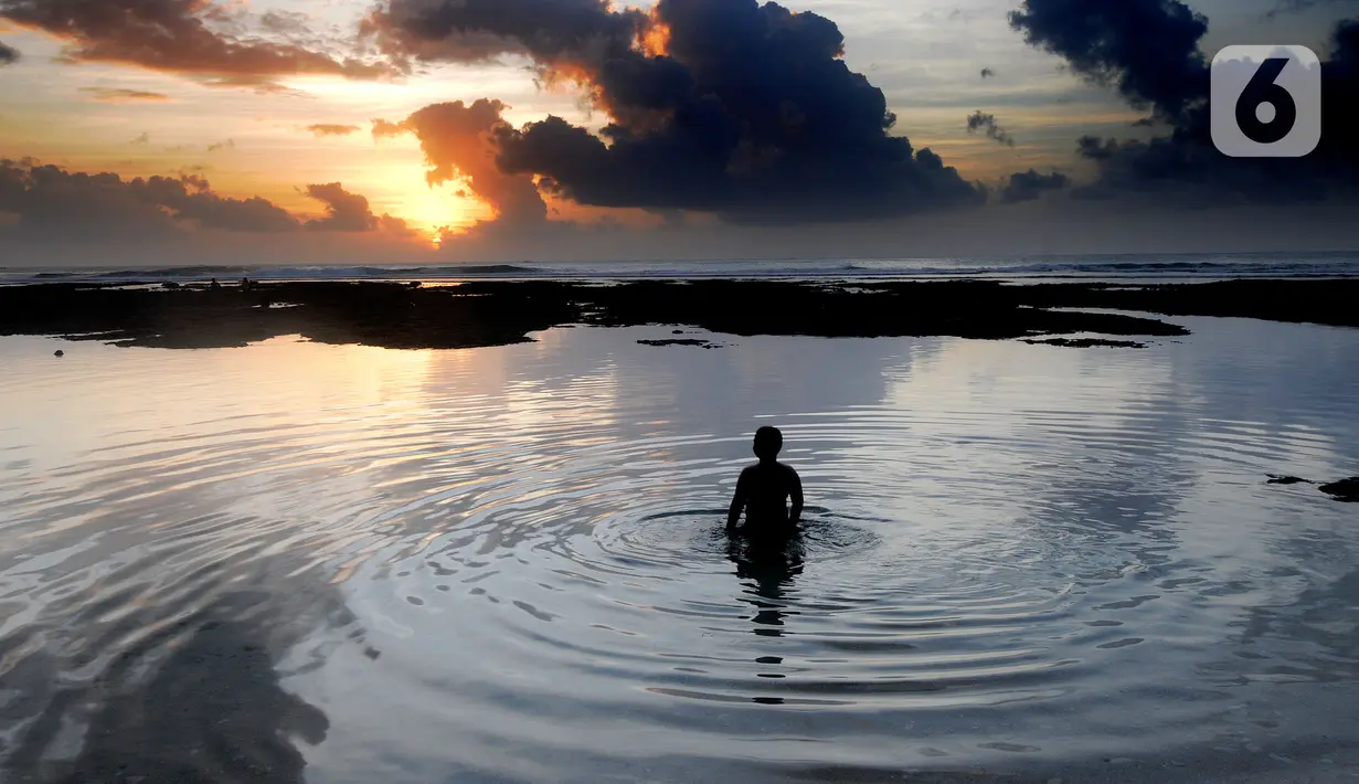 Wisatawan berendam di kolam renang alami yang terbentuk saat air laut surut di kawasan Pantai Suluban, Uluwatu, Bali, Selasa (7/9/2021). Keunikan Pantai Suluban dengan kolam-kolam yang terbentuk di atas karang menjadi daya tarik wisatawan. (merdeka.com/Arie Basuki)
