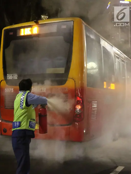 Petugas menyemprotkan apar ke TransJakarta yang mengeluarkan asap dari dalam mobil di Bundaran HI, Jakarta, Rabu (25/4) malam. Dalam kejadian tersebut para penumpang berhasil keluar dengan selamat. (Liputan6.com/Angga Yuniar)