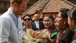 Pangeran Harry menerima buket bunga dari Panchakanya atau lima perawan khas budaya tradisional Nepal saat mengunjungi salah satu situs warisan dunia, Patan Durbar Square di Kathmandu, Minggu (20/3). (REUTERS/Prakash Mathema/Pool)