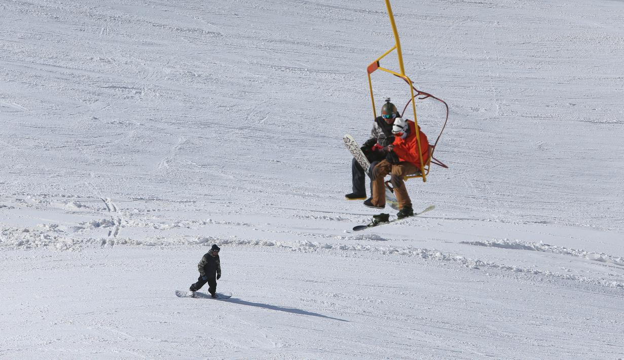 Pemain ski menuruni lereng saat dua orang lainnya duduk di kereta gantung resor ski Dizin, sebelah utara ibu kota Tehran, Iran, Kamis (8/3). Dizin merupakan salah satu yang resor ski es yang terletak di pegunungan Alborz Iran. (AP Photo/Vahid Salemi)