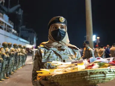 Nour Al-Ghanmi dari Angkatan Laut Kerajaan Arab Saudi membawa nampan berisi permen untuk menyambut warga yang dievakuasi dari Sudan di Pelabuhan Jeddah, Arab Saudi, Senin (24/4/2023). ( Saudi Ministry of Media via AP)
