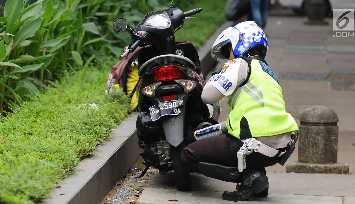 Petugas kepolisian menggembosi ban motor yang parkir di trotoar Jalan Kebon Sirih, Jakarta, Senin (17/7). Hal ini tindak lanjut maraknya pelanggaran lalu lintas di kawasan pedestrian Jalan Kebon Sirih. (Liputan6.com/Helmi Fithriansyah)