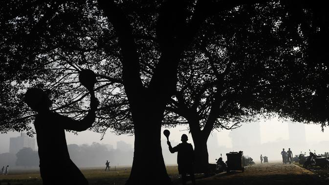 Siswa bermain di pagi yang berkabut di taman Maidan di Kolkata (29/11/2019). Taman Maidan  dipenuhi dengan patung-patung dan karya-karya seni bina, yang paling ketara ialah Peringatan Victoria. (AFP Photo/Dibyangshu Sarkar)