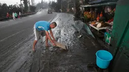 Warga membersihkan jalanan dari abu vulkanik setelah erupsi Gunung Taal di Tagaytay, Provinsi Cavite, Filipina, Senin (13/1/2020). Gunung yang terakhir meletus pada tahun 1977 tersebut melontarkan abu vulkanik mencapai 50.000 kaki (15.000 meter) ke atmosfer. (AP Photo/Aaron Favila)