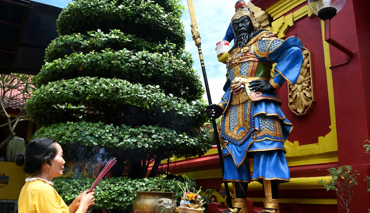 Seorang wanita berdoa di kuil Cina di Denpasar, Bali, Senin (23/1). Warga Konghucu Bali  menghias kuil mereka dalam rangka menyambut pergantian tahun baru Imlek 2568. (AFP PHOTO / SONNY Tumbelaka)