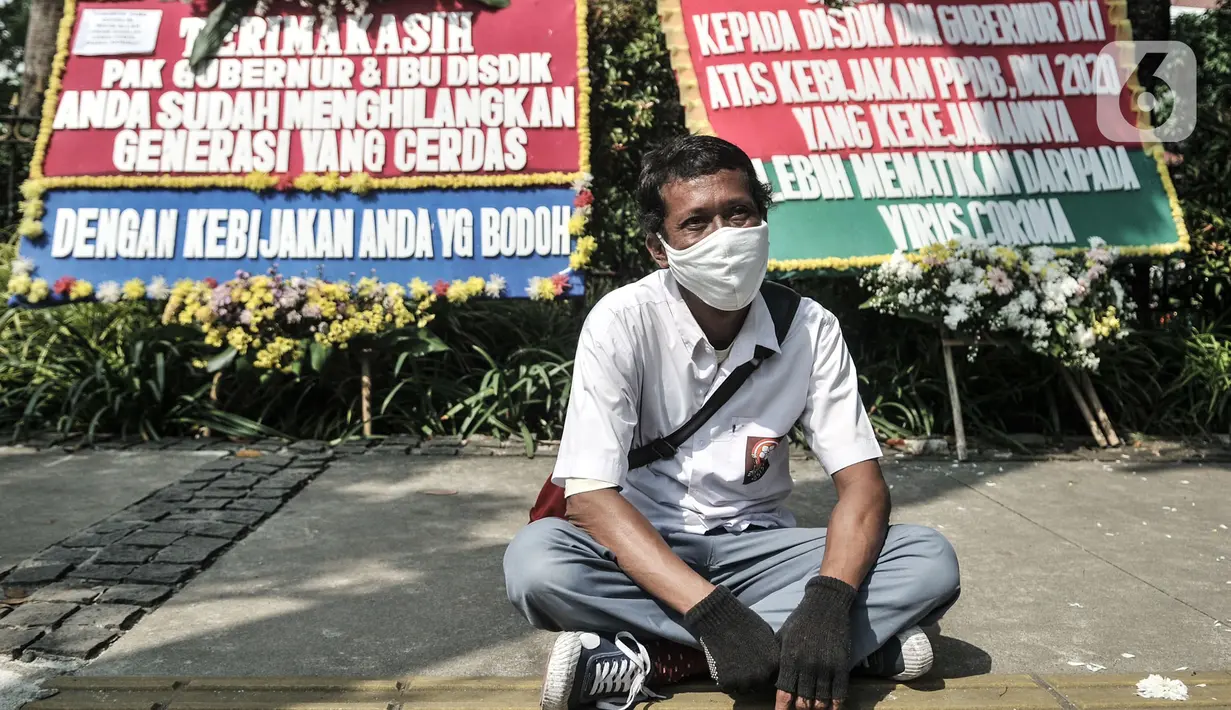 Massa dari Relawan PPDB DKI Jakarta 2020 duduk di depan karangan bunga yang terpajang di Balai Kota DKI Jakarta, Senin (6/7/2020). Karangan bunga itu bentuk kekecewaan terhadap Gubernur Anies Baswedan dan Kadisdik DKI terkait penerimaan siswa baru Jalur Zonasi. (merdeka.com/Iqbal Nugroho)