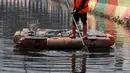 Petugas PPSU membersihkan sampah yang tertutup jaring hitam di Kali Item, Kemayoran, Jakarta, Jumat (20/7). Pemasangan jaring dilakukan untuk menutupi keruhnya air dan bau tak sedap di Kali Item. (Liputan6.com/Arya Manggala)