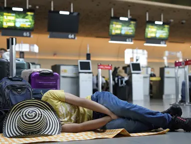 Seorang penumpang maskapai Viva Air tidur di bandara setelah maskapai berbiaya rendah itu menangguhkan operasinya di Bandara Internasional El Dorado di Bogota, Kolombia, Selasa (28/2/2023). Maskapai sedang menunggu penyelesaian proses integrasi dengan sekelompok maskapai penerbangan yang harus disetujui oleh otoritas Kolombia. (AP Photo/Fernando Vergara)