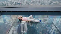Wisatawan tiduran di dek kaca gedung King Power Mahanakhon, Bangkok, Thailand, Rabu (21/11). Gedung King Power Mahanakhon memiliki 78 lantai. (AP Photo/Sakchai Lalit)