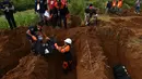Petugas membongkar tas tubuh yang berisi sisa-sisa korban pengepungan Marawi saat pemakaman massal di sebuah pemakaman umum di Marawi, di pulau selatan Mindanao (24/7). Perang di Marawi memasuki bulan kedua. (AFP Photo/Ted Aljibe)