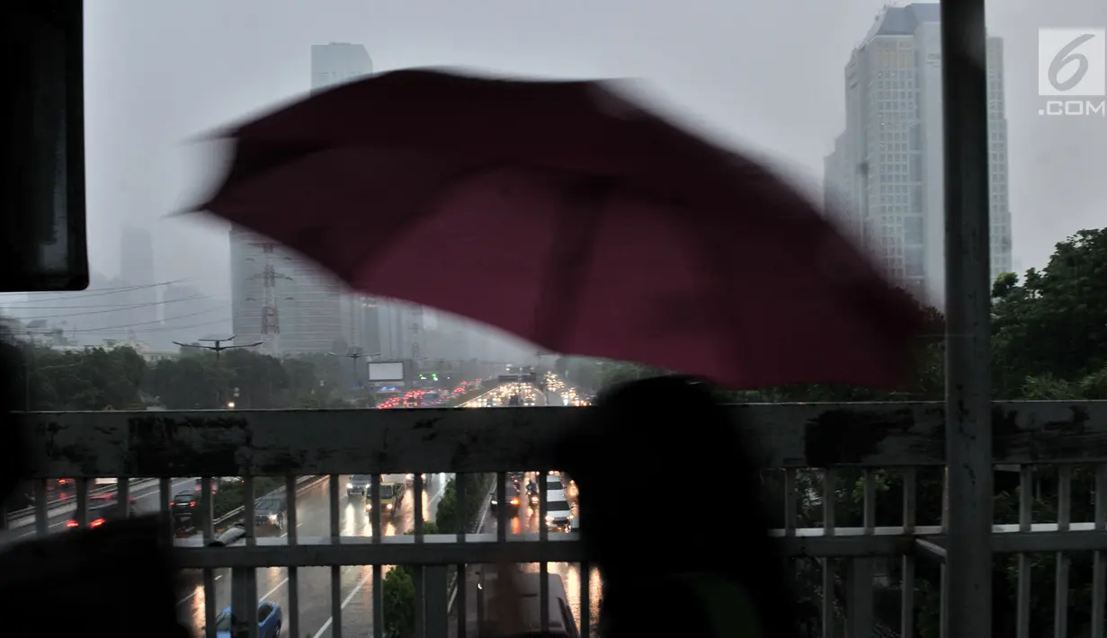 Pejalan kaki menggunakan payung saat hujan deras mengguyur kawasan Gatot Soebroto, Jakarta, Senin (11/2). Badan Meteorologi, Klimatologi, dan Geofisika (BMKG) memprediksi puncak musim hujan terjadi hingga Februari 2019. (Merdeka.com/Iqbal Nugroho)