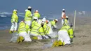 Pekerja dengan pakaian pelindung membersihkan pantai yang terkontaminasi tumpahan minyak di Huntington Beach, California, Amerika Serikat, Selasa (5/10/2021). Kebocoran pipa menyebabkan tumpahan minyak di lepas pantai California. (AP Photo/Ringo H.W. Chiu)