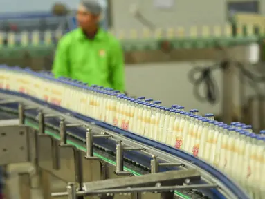 Pekerja memantau jalur produksi susu kedelai di sebuah pabrik di Nanning, Guangxi, China, Selasa (12/3). Produksi industri China turun ke level terendah dalam 17 tahun terakhir. (STR/AFP)