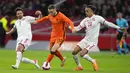 Pemain Belanda Teun Koopmeiners (tengah) berebut bola dengan pemain Denmark Thomas Delaney (kiri) dan Yussuf Poulsen pada pertandingan persahabatan di Johan Cruyff ArenA, Amsterdam, Belanda, 26 Maret 2022. Belanda menang 4-2. (AP Photo/Peter Dejong)