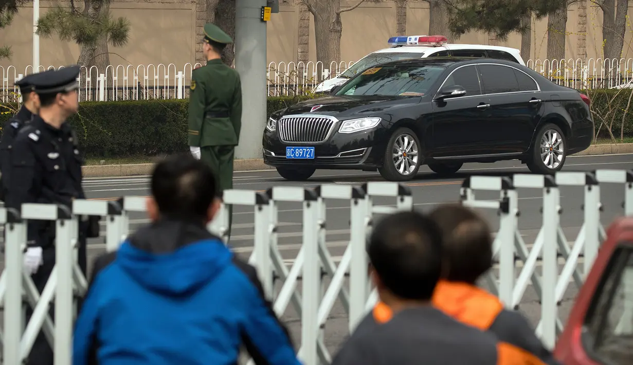 Polisi dan petugas keamanan berjaga ketika iring-iringan mobil berjalan di sepanjang jalan dekat Wisma Negara Diaoyutai, Beijing, Selasa (27/3). Kabar yang berkembang menyebut Pemimpin Korea Utara Kim Jong-un tiba di Beijing. (AP Photo/Mark Schiefelbein)