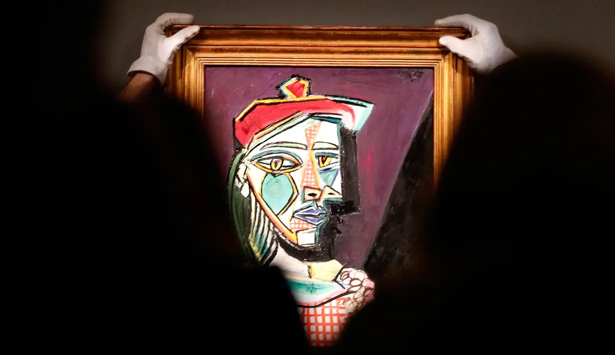 Petugas rumah lelang Sotheby menata lukisan Pablo Picasso bernama Femme au beret et a la robe quadrillee pada sesi pemotretan di London, Rabu (22/2). Lukisan berwarna-warni tersebut menggambarkan kekasih Prancis sang maestro itu. (AP/Frank Augstein)